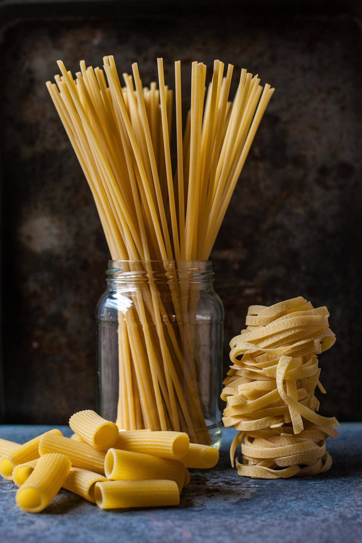 Three types of uncooked pasta on a countertop.