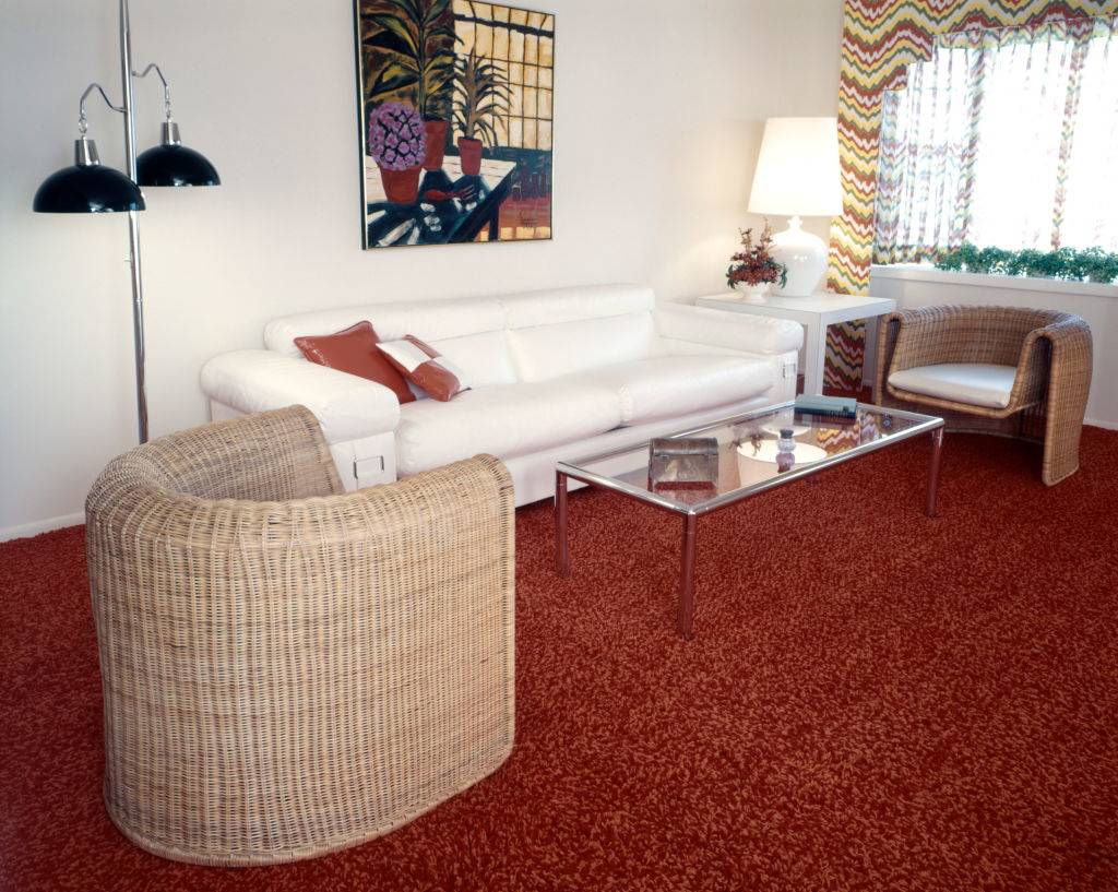 living room with red carpet, white couch, glass coffee table, and lamps