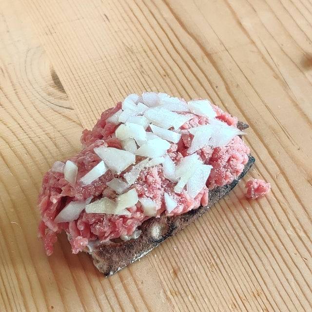 Raw ground beef, raw white onion and pepper on bread