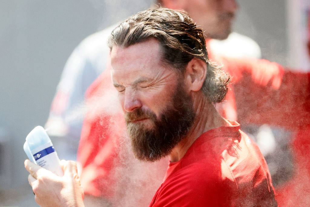 baseball player applying spray sunscreen to his face
