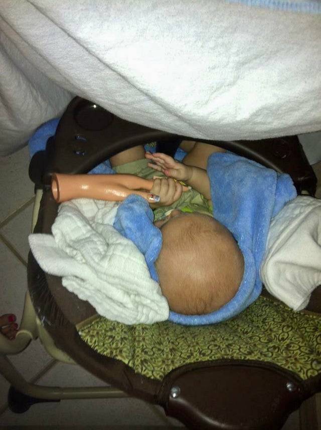 Baby holding fake prosthetic hand to fall asleep