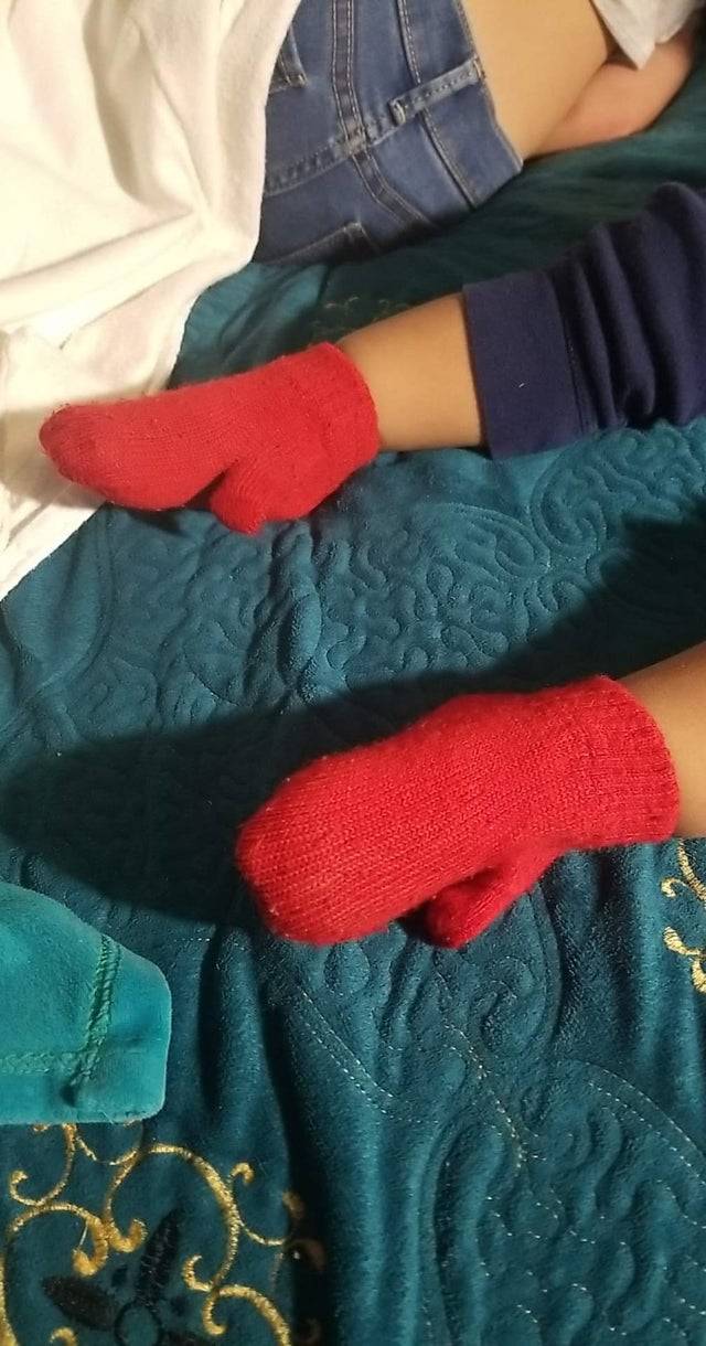 Red wooly mittens as socks on little boy's feet