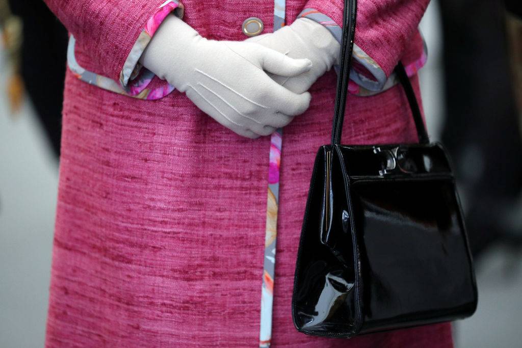 Queen Elizabeth II holds her Launer black handbag