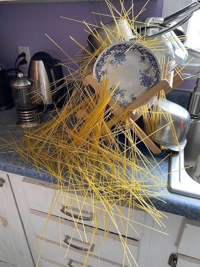 Spilled spaghetti noodles that have bunched together all over the counter and dish drying rack