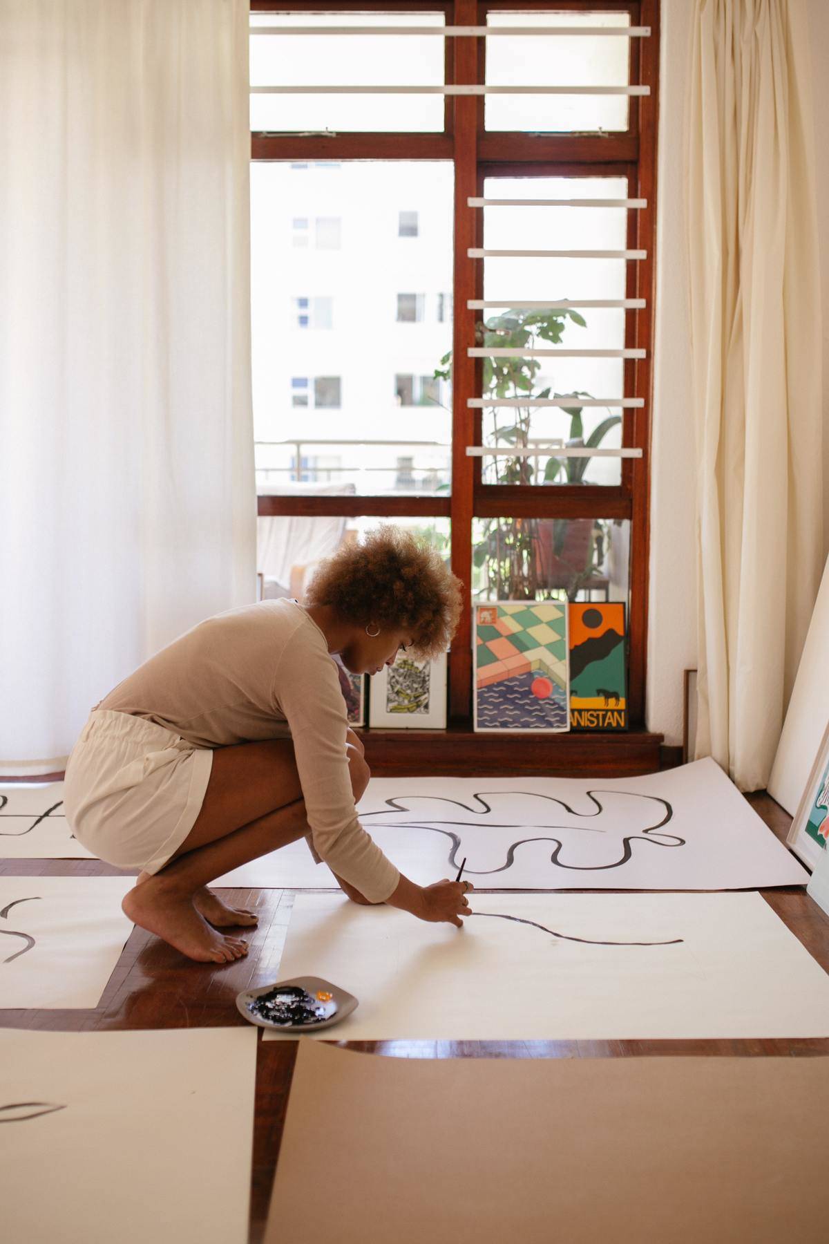 Woman painting on sheets of paper spread out on floor