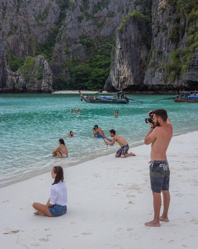Several boyfriends all take posed photos of their girlfriends at the beach. 
