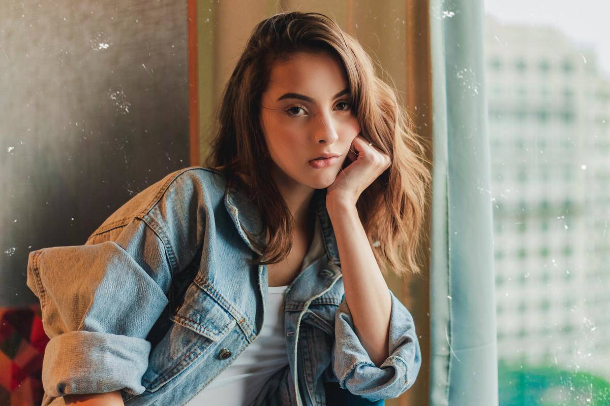 Woman looks bored sitting near building window