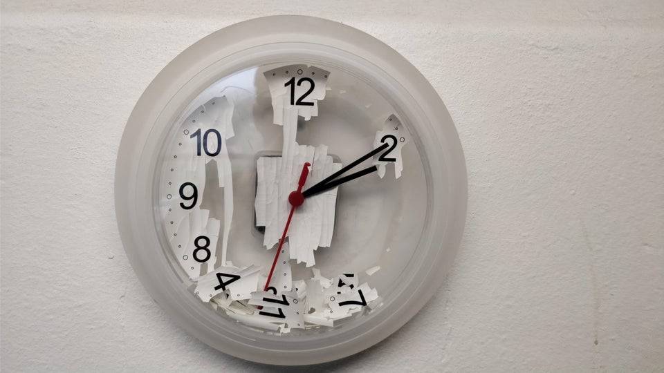 Plastic clock on the wall with many of the numbers fallen inside.
