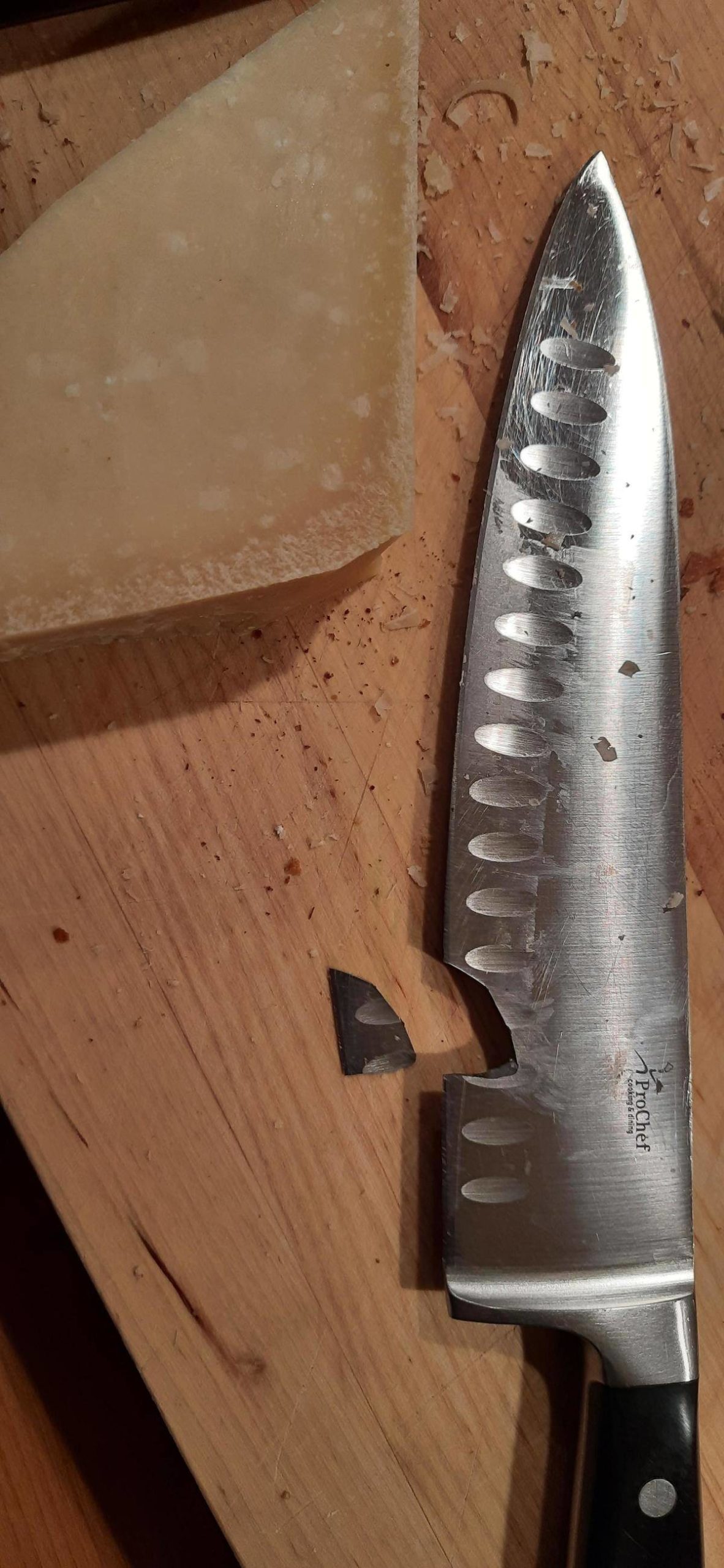 Knife with a chunk of the blade broken off beside a piece of cheese.