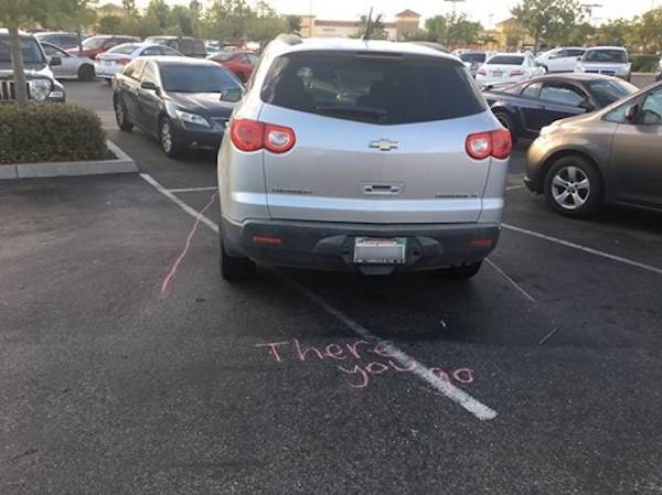 SUV parked sideways in parking space and chalked lines showing where the new spot would be.