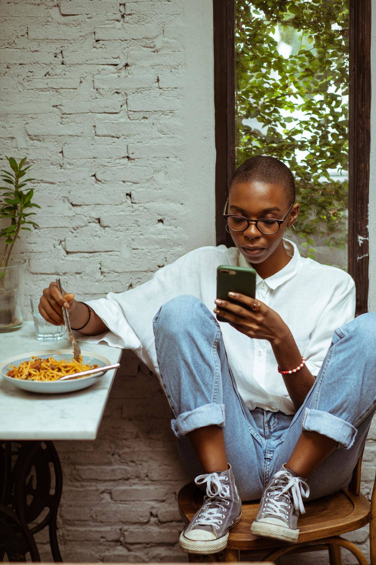 Woman eating at table checking phone