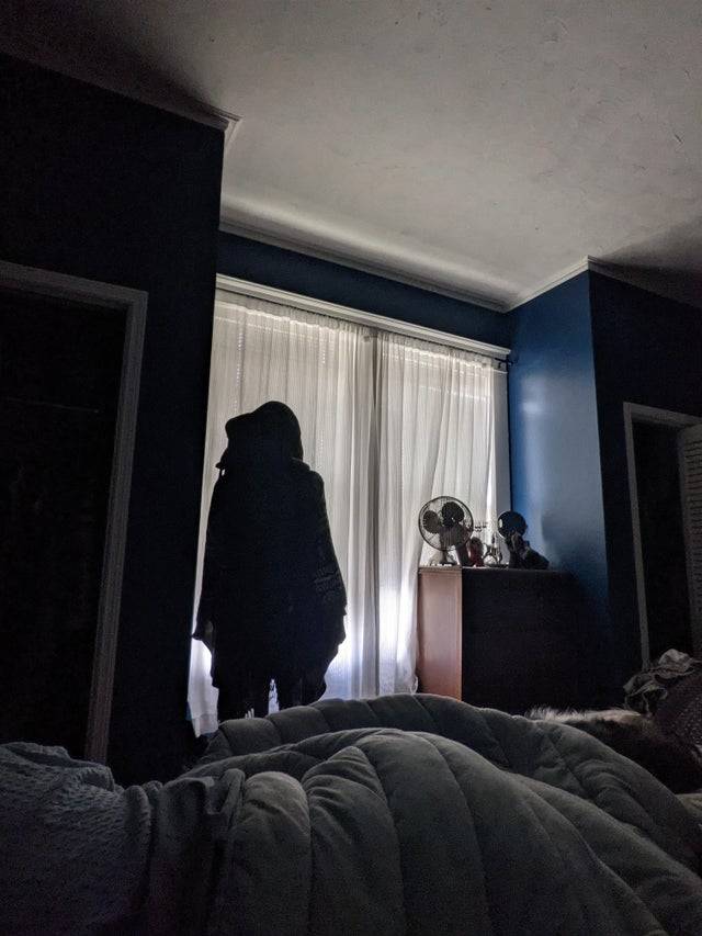 Coatrack in bedroom looks like person in hooded coat