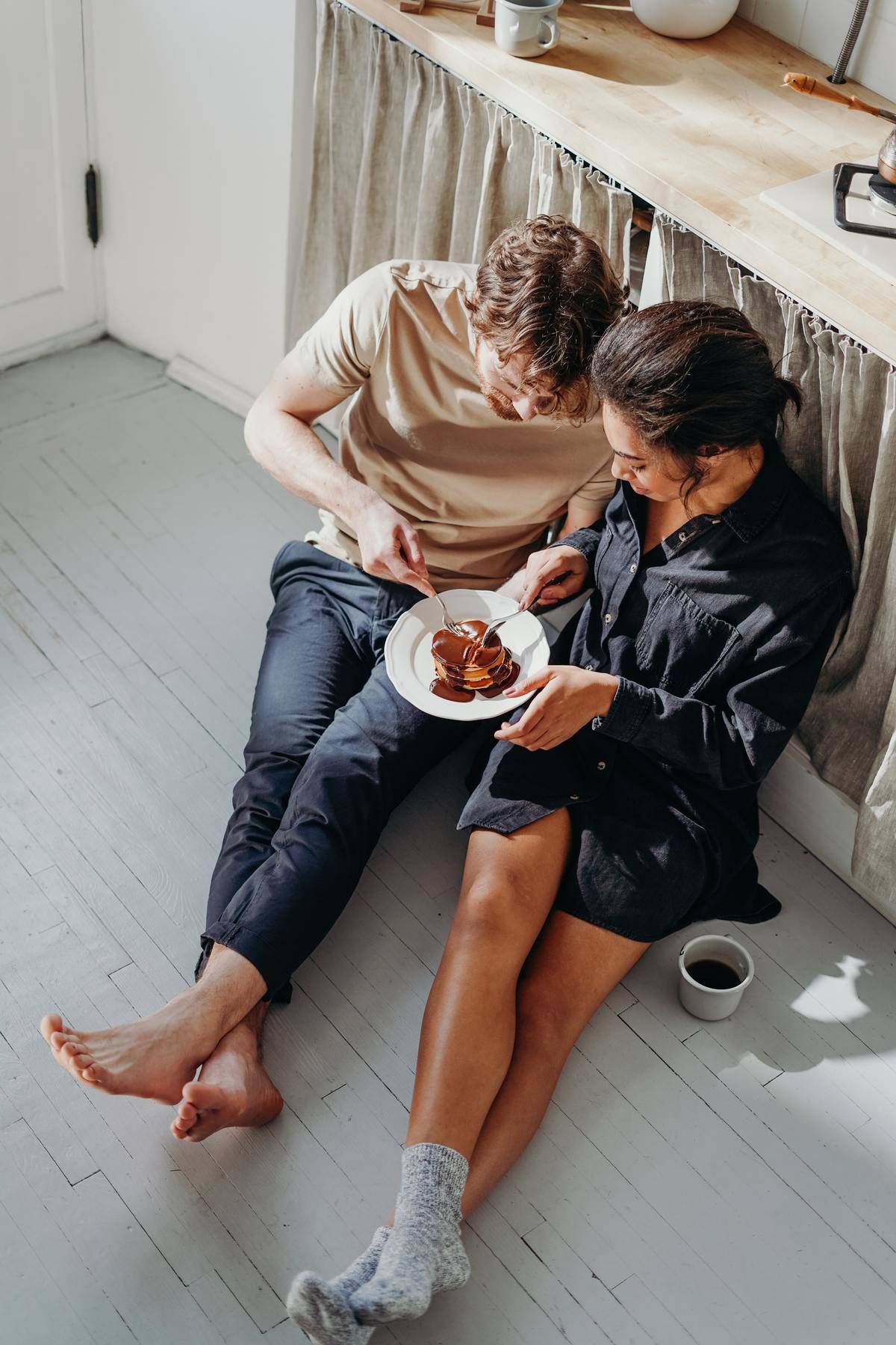 Couple eats breakfast from same plate while seated on floor