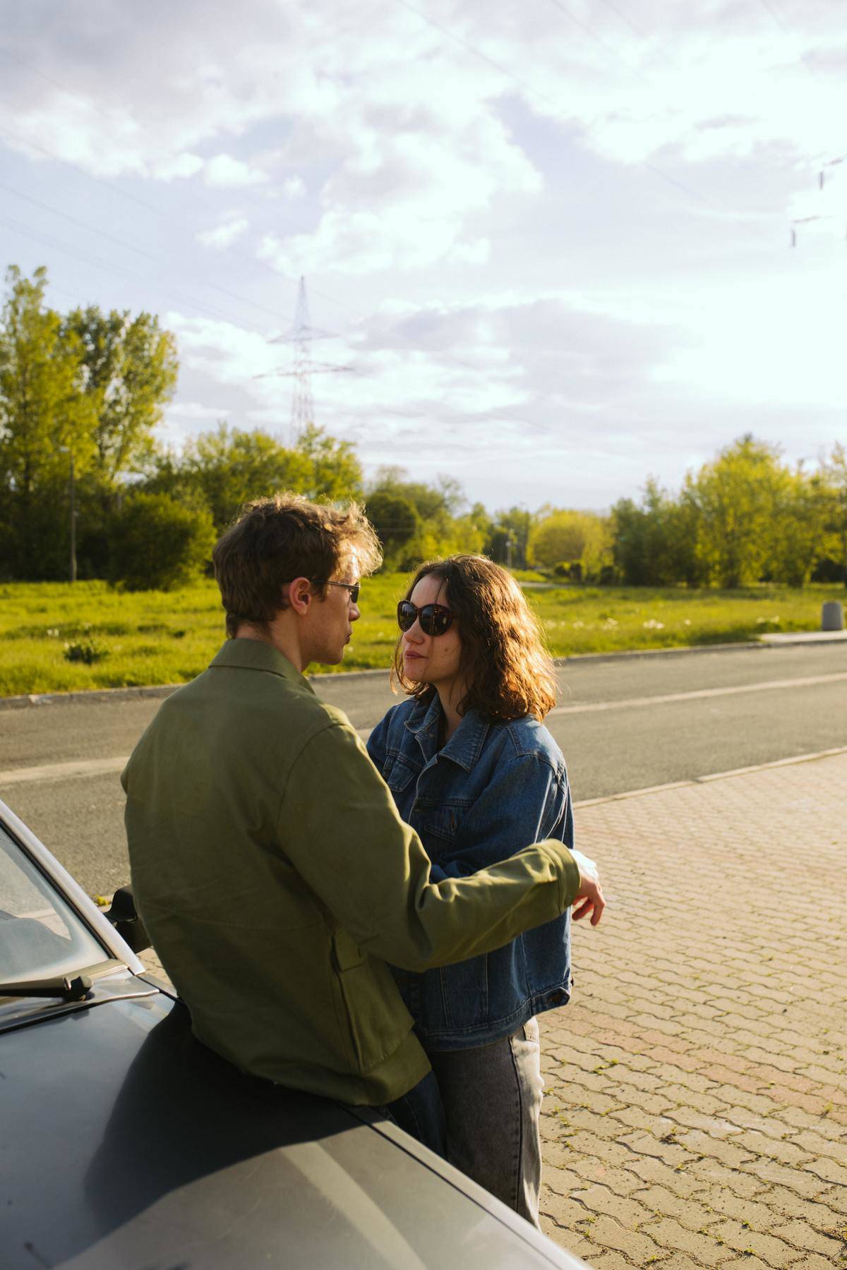 Couple leans against vehicle hood outside 