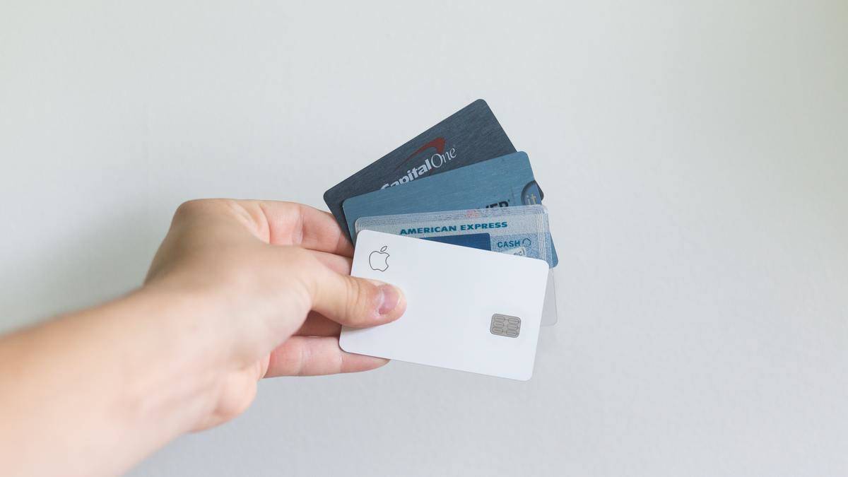 A person holds several credit cards, including American Express and Capital One. 
