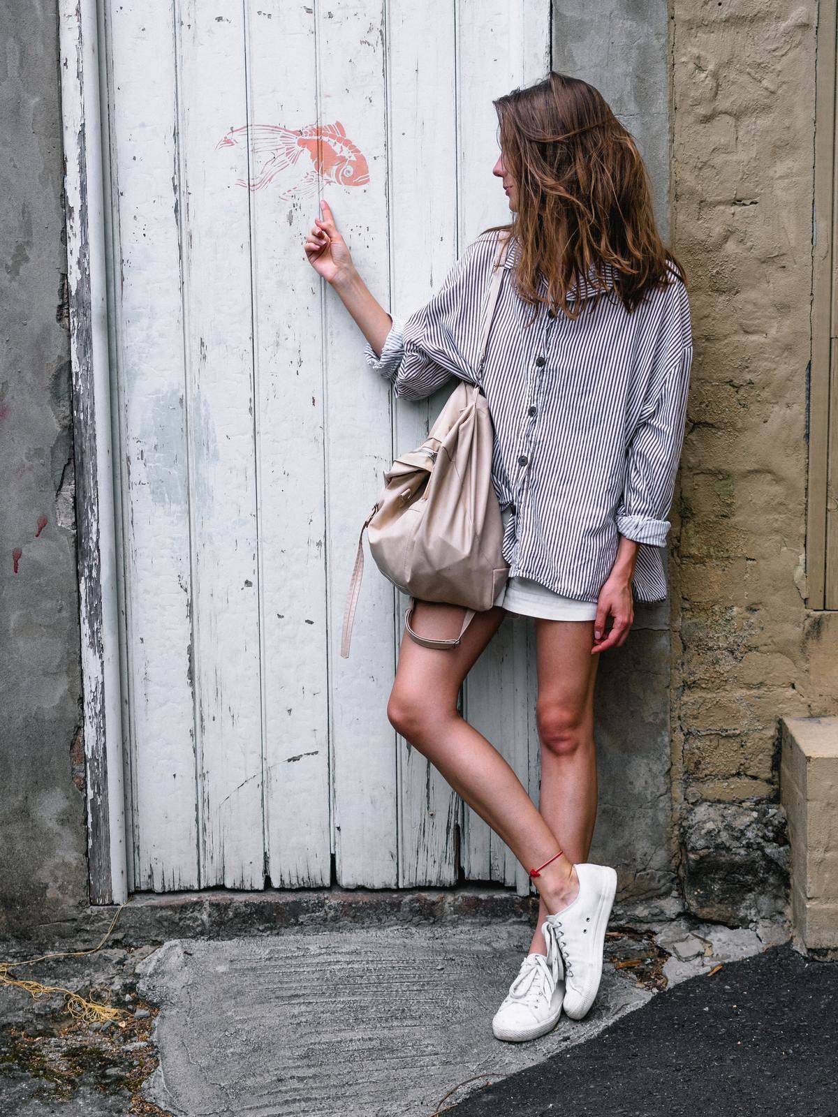 Woman looks at fish painting on old worn wooden door