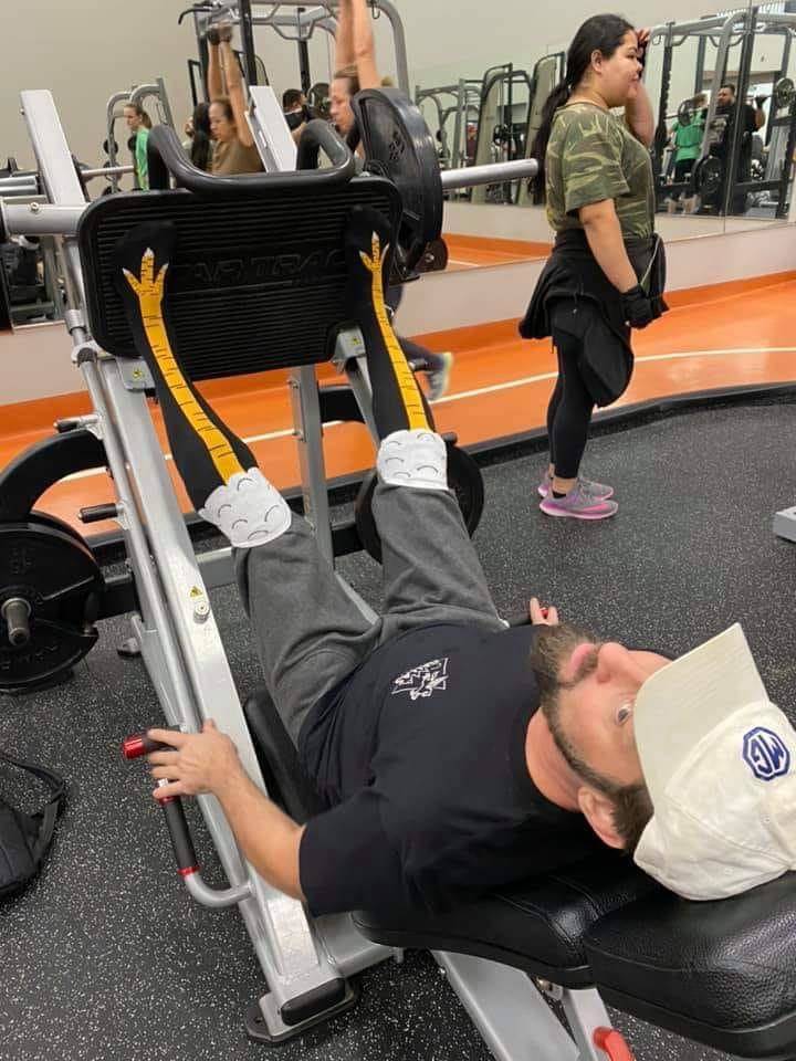Man wearing chicken leg socks while using leg press at the gym