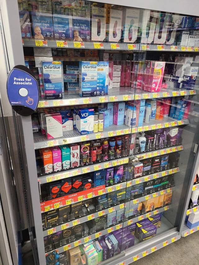 Locked lubricants and vibrators in cabinet at store with button that says Press For Help