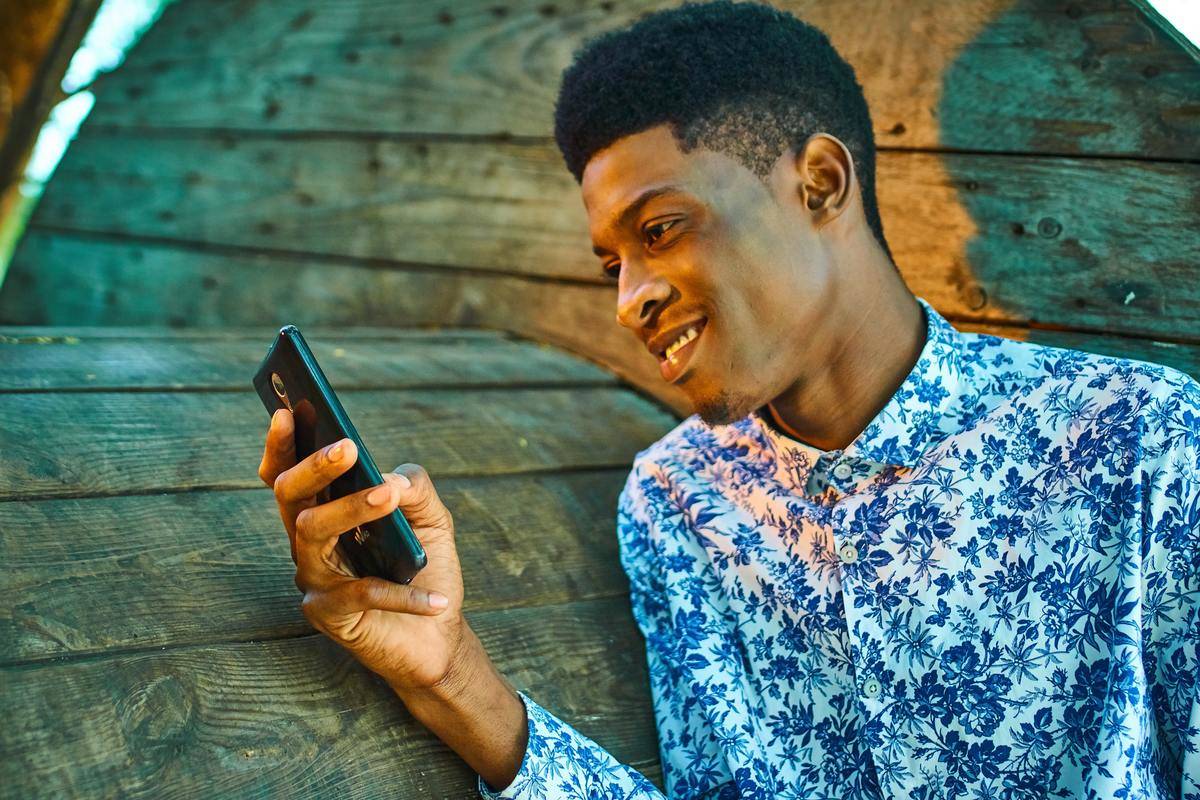 A man smiles while using his cell phone.