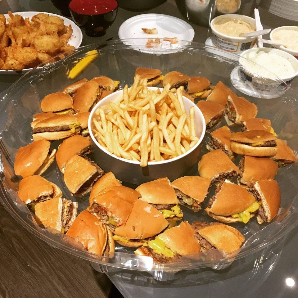 Tray of McDonald's burgers cut into quarters with a bowl of fries in the middle