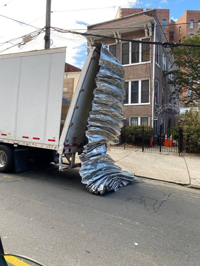 Transport truck with the roof dangling off of the back. 