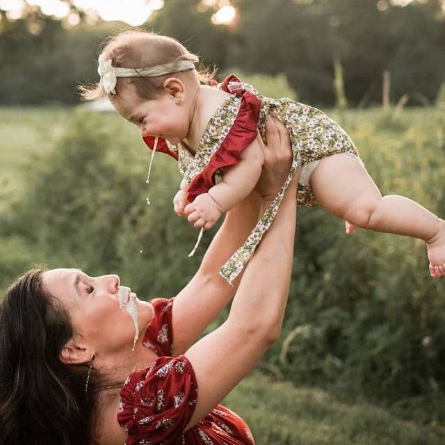 Mom holding up baby that is throwing up on her.