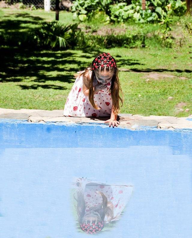 Girl looking into a pool with an edited reflection that is not where it should be.