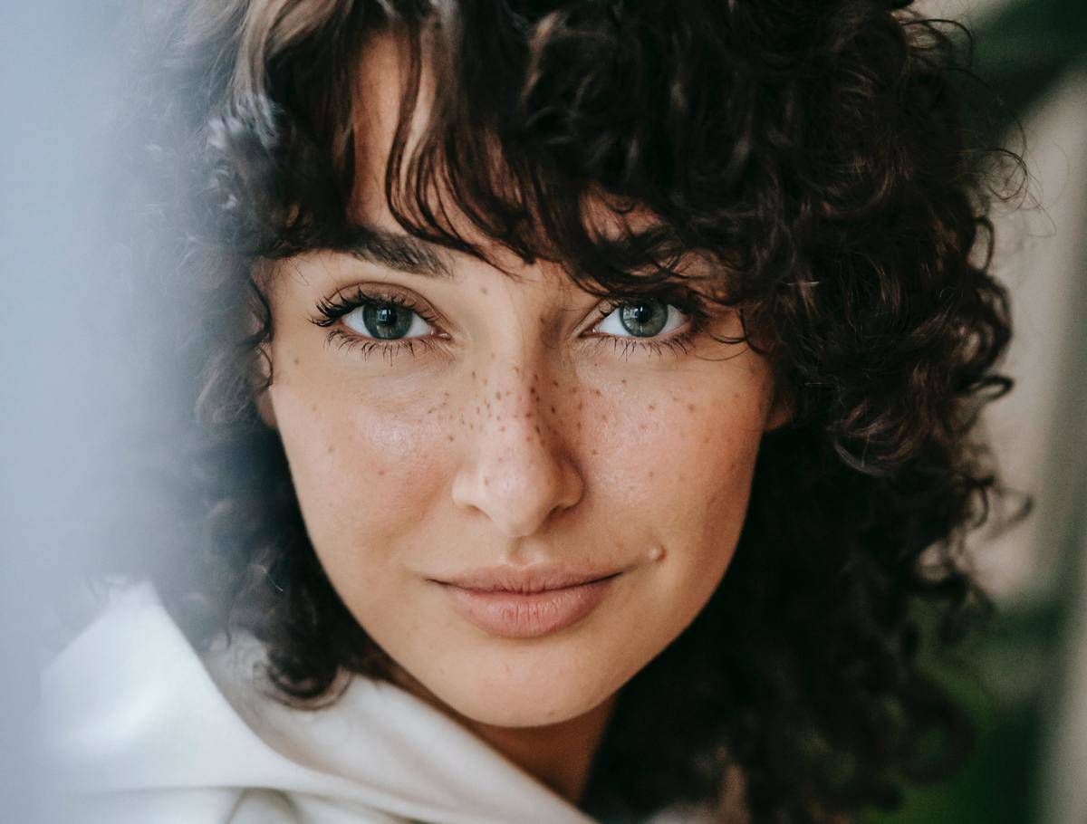 Portrait shot of woman with dark curly hair and freckles