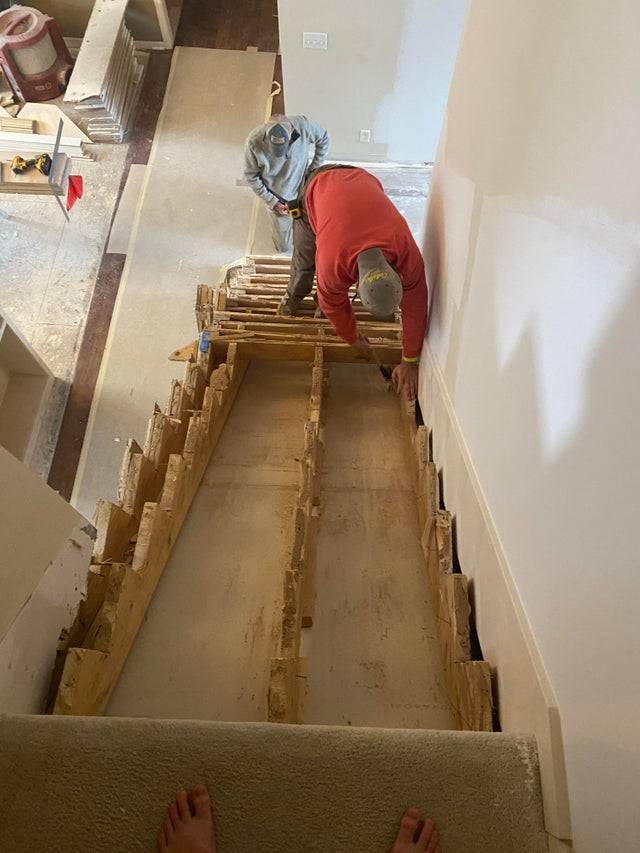 A man at the bottom of a staircase where the stairs have been removed