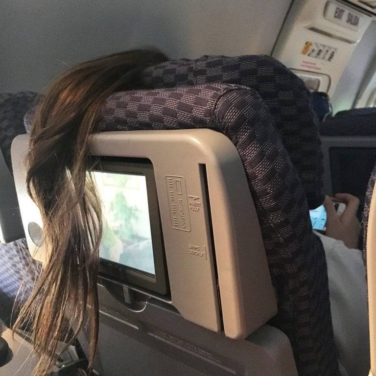 Passenger's ponytail is over the top of her seat and covering the TV of the passenger behind her. 