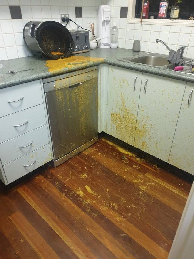 A tipped slow cooker and curry all over a kitchen