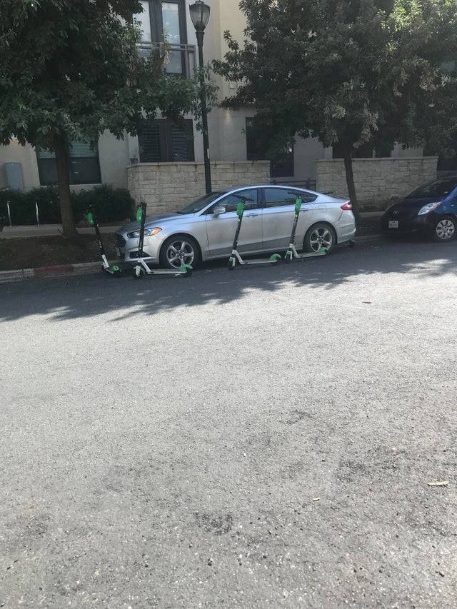Car with scooters parked around it.