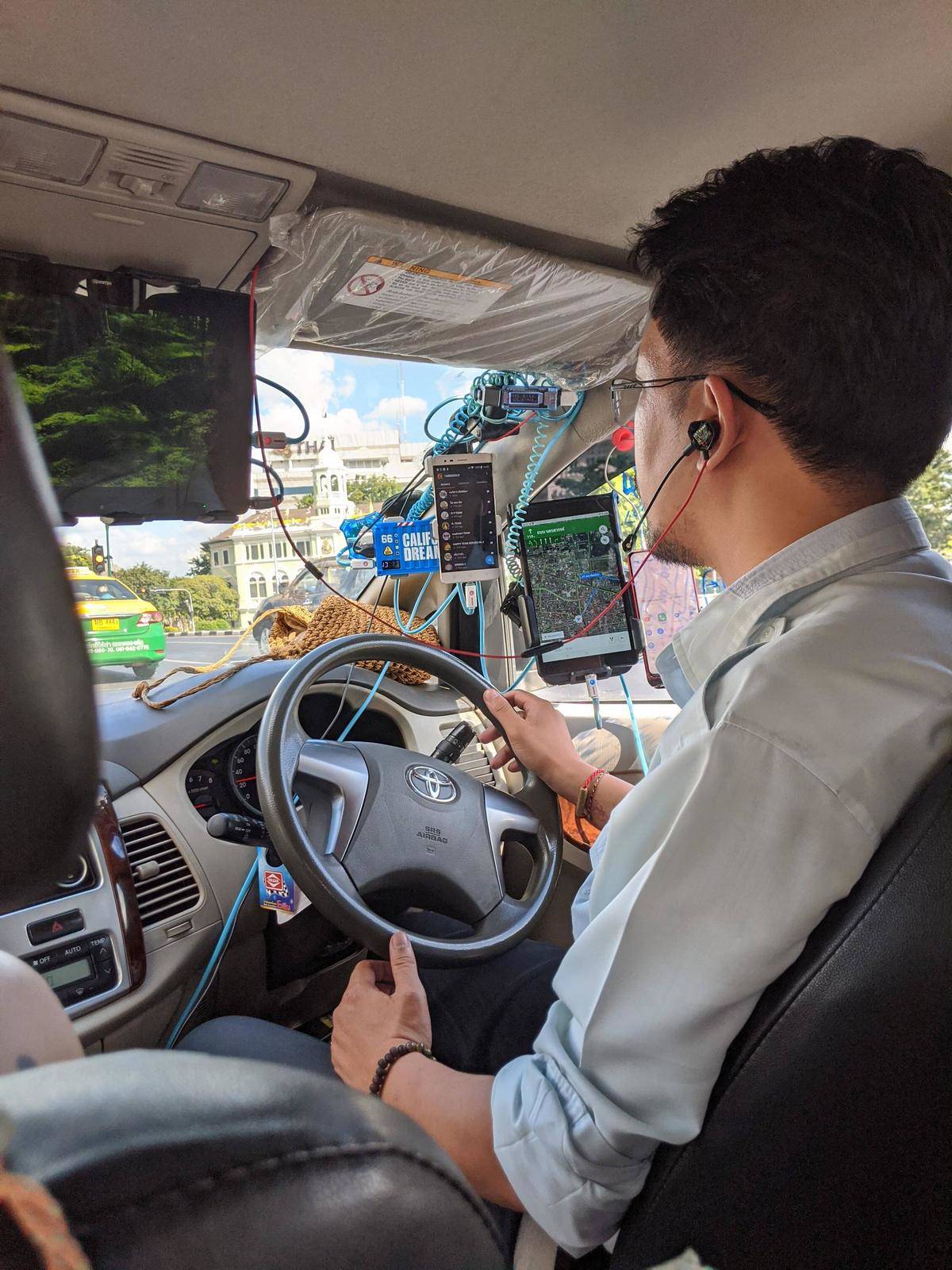 Taxi driver with many screens by the steering wheel. 