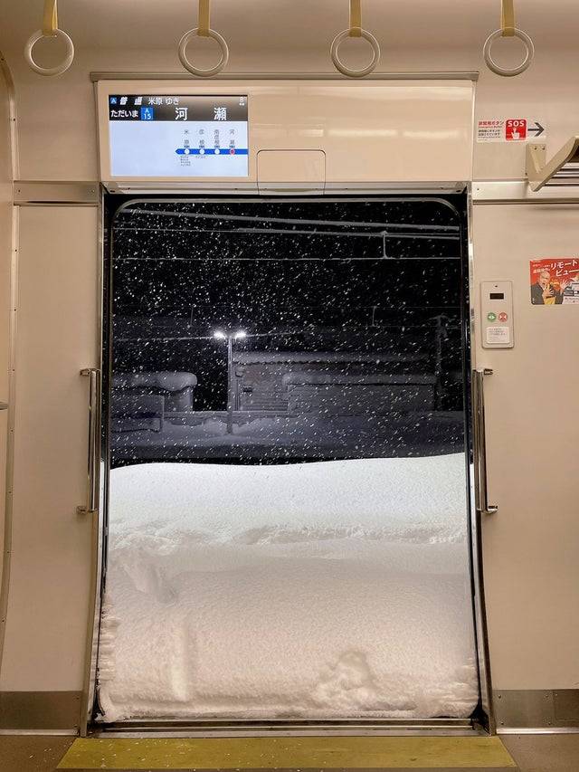 Train doors open at a stop and the platform is covered in 2-3 feet of snow.
