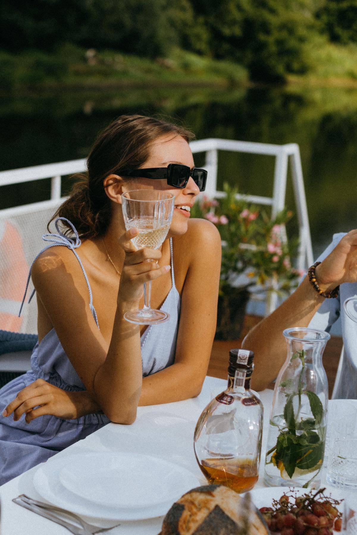 Woman in sunglasses sips wine and smiles