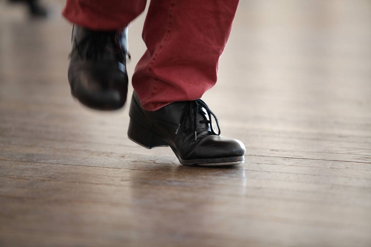 A person wearing red pants and black shoes tap dances.