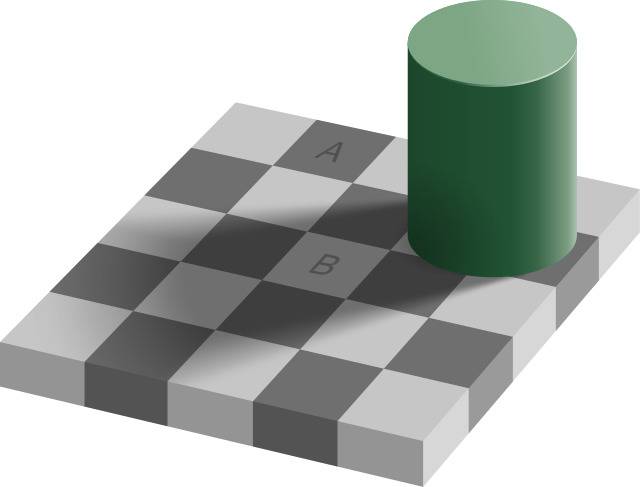 Green cylinder in the corner of a two-toned grey checkered board