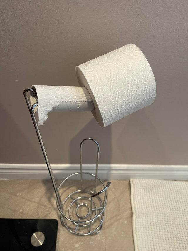 Woman changes a toilet paper roll by putting the new roll on top of the old one.