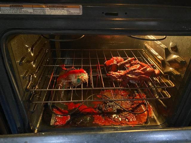 Open oven with burnt and melted food inside. 