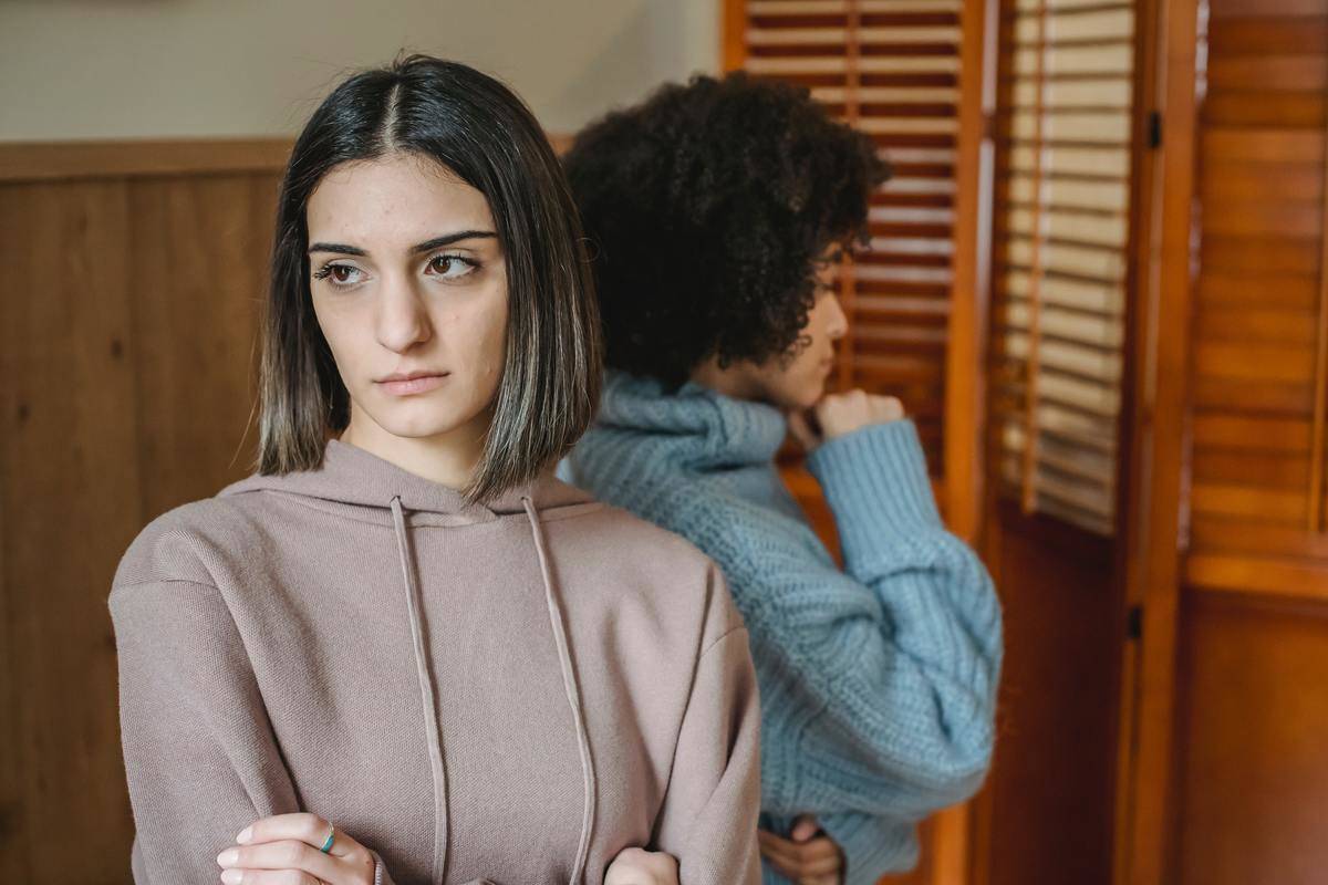 Two woman back to back looking annoyed staring off into distance