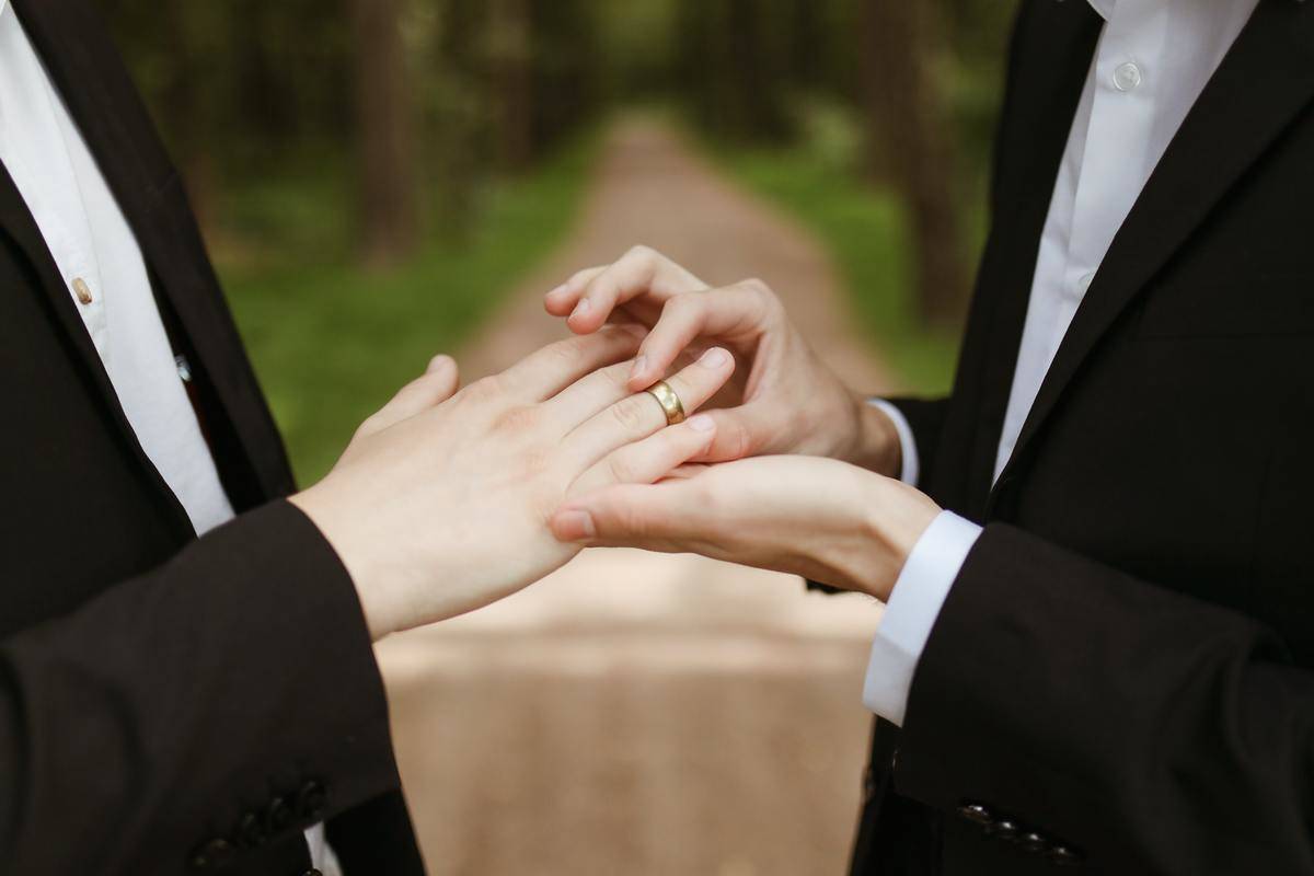 A man puts a wedding ring on his spouse.