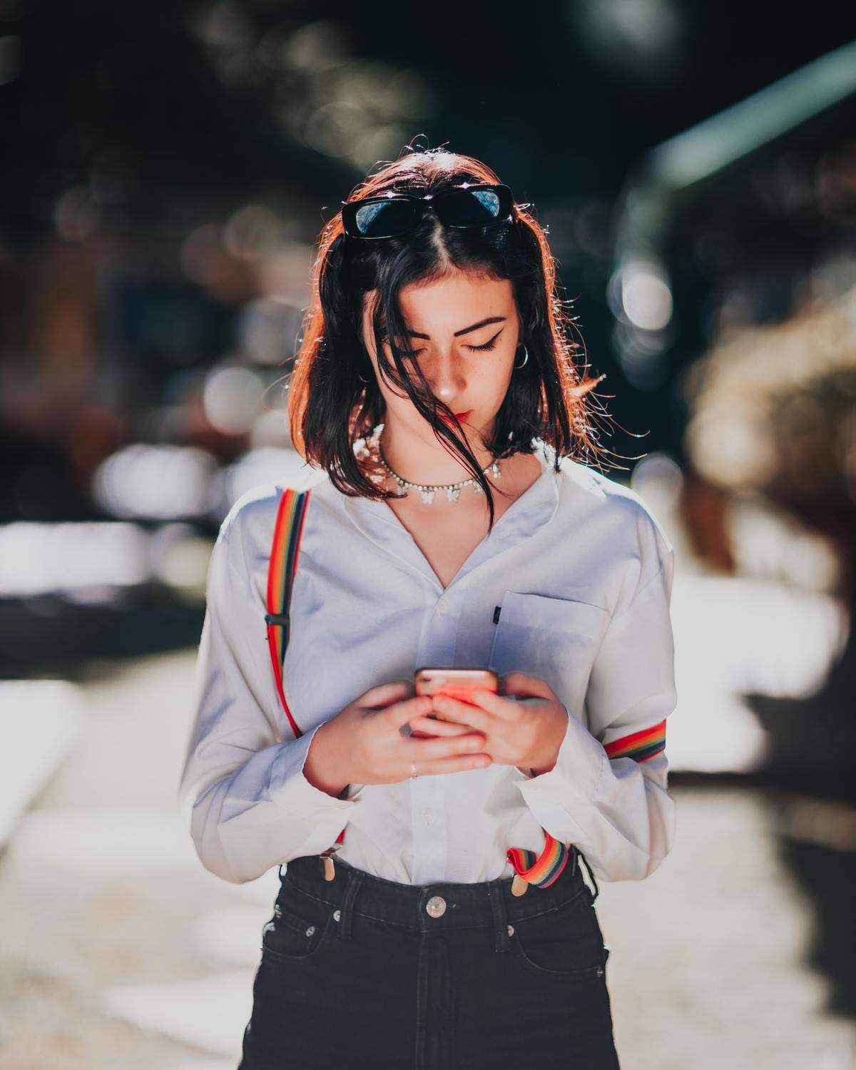 Woman checking cell phone while standing in street
