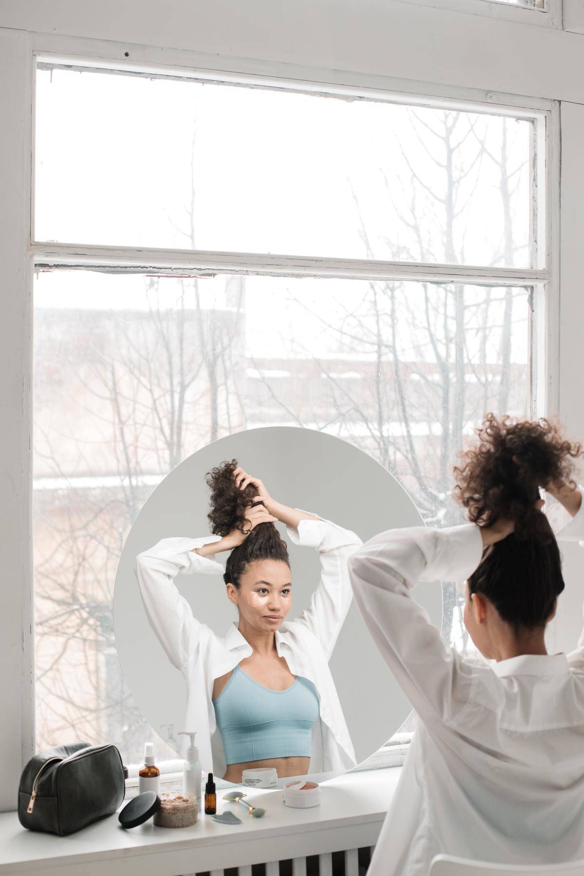 Woman does her hair looking in the mirror