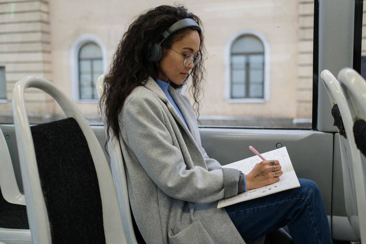 Woman sits on bus minding her own business and wearing headphones.