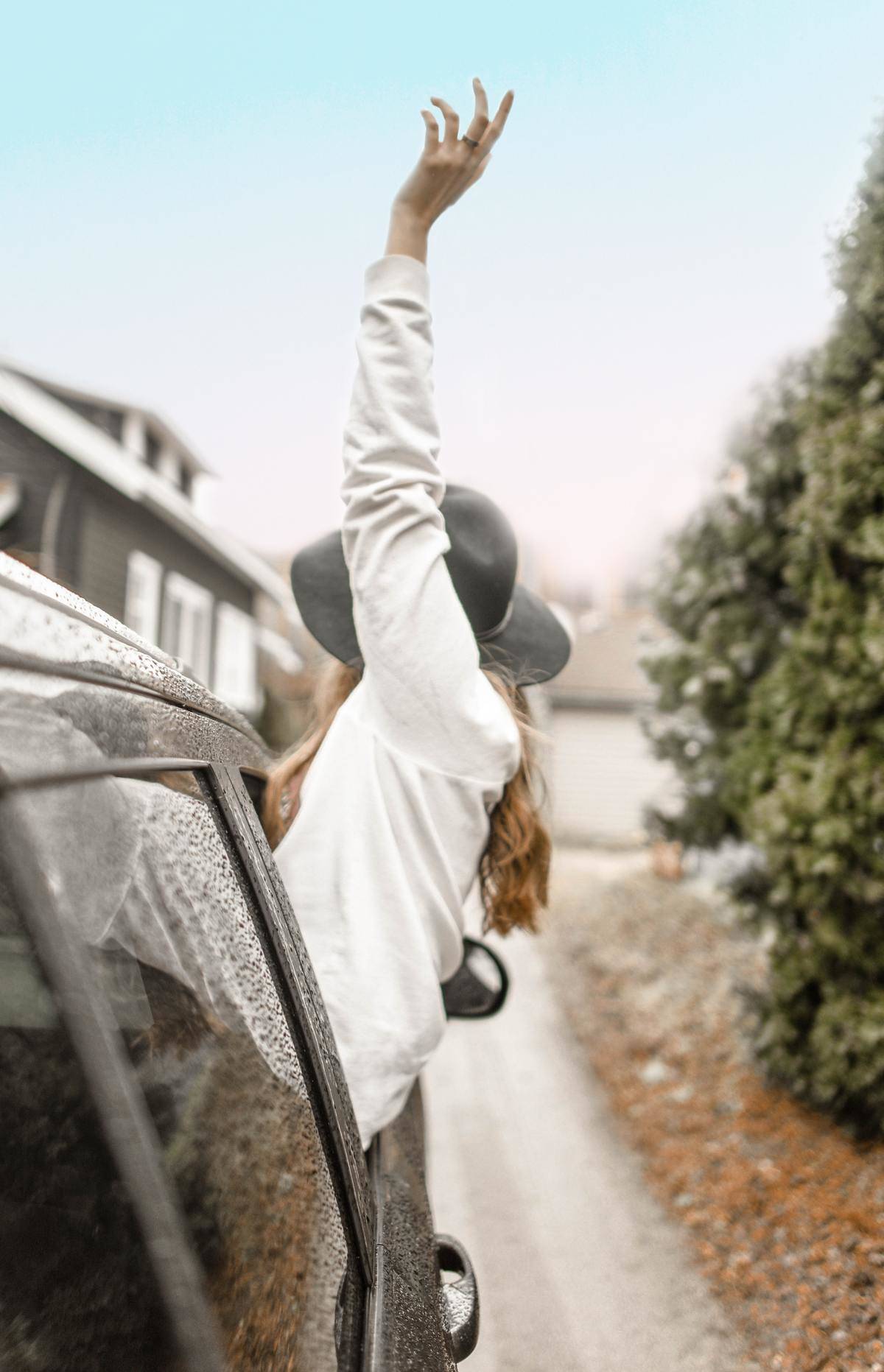 Woman with arm outstretched leaning out car window