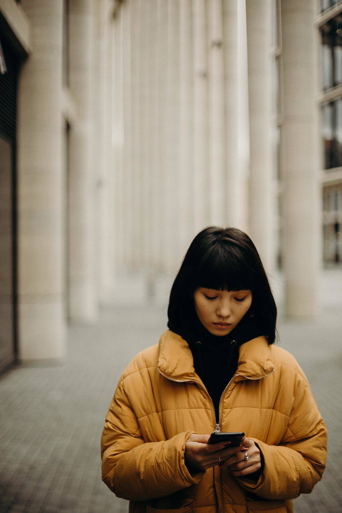 Woman texting outside wearing yellow puffer jacket
