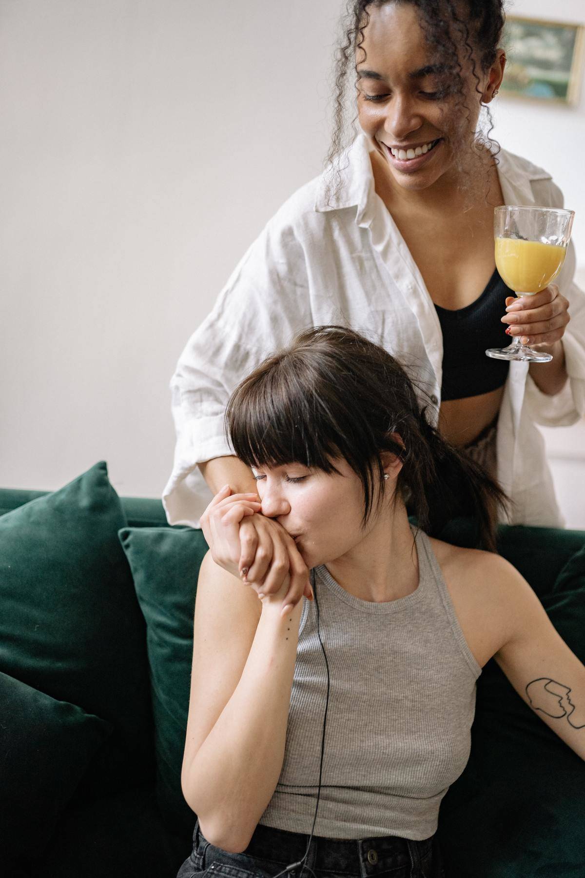 Woman on couch kisses standing woman's hand