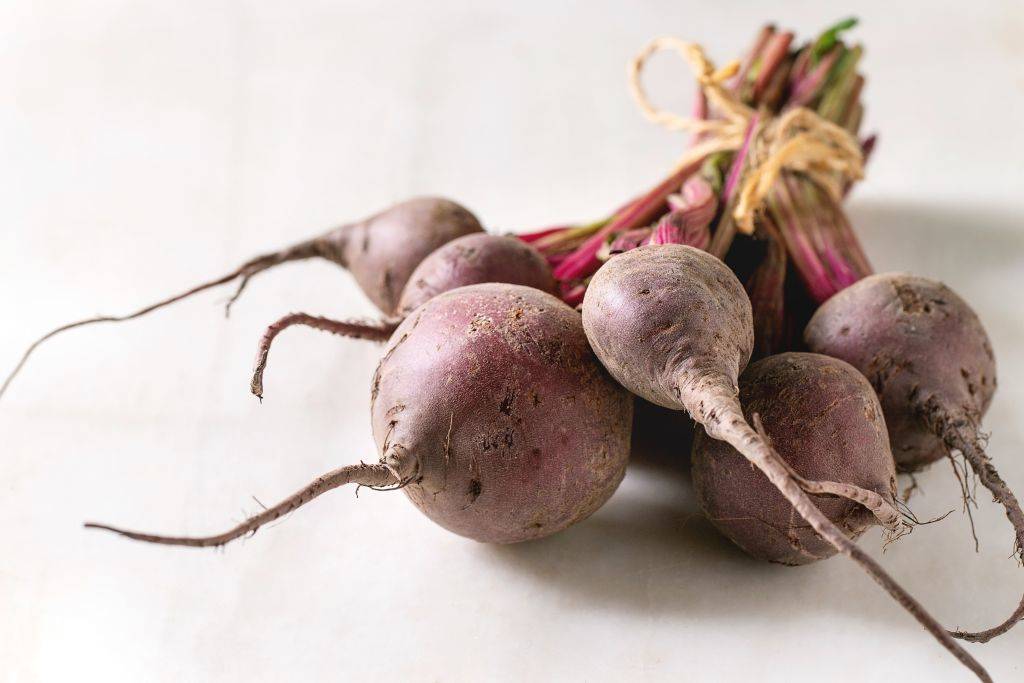 Bundle of young organic garden beetroot over white marble background