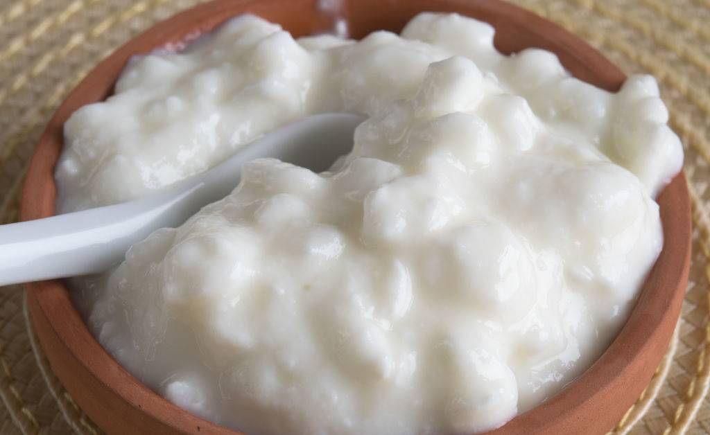 cottage cheese in a clay bowl with a spoon