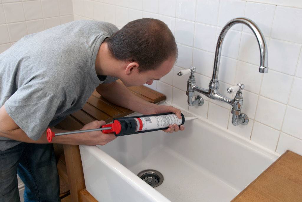 Man using sealant gun in a kitchen